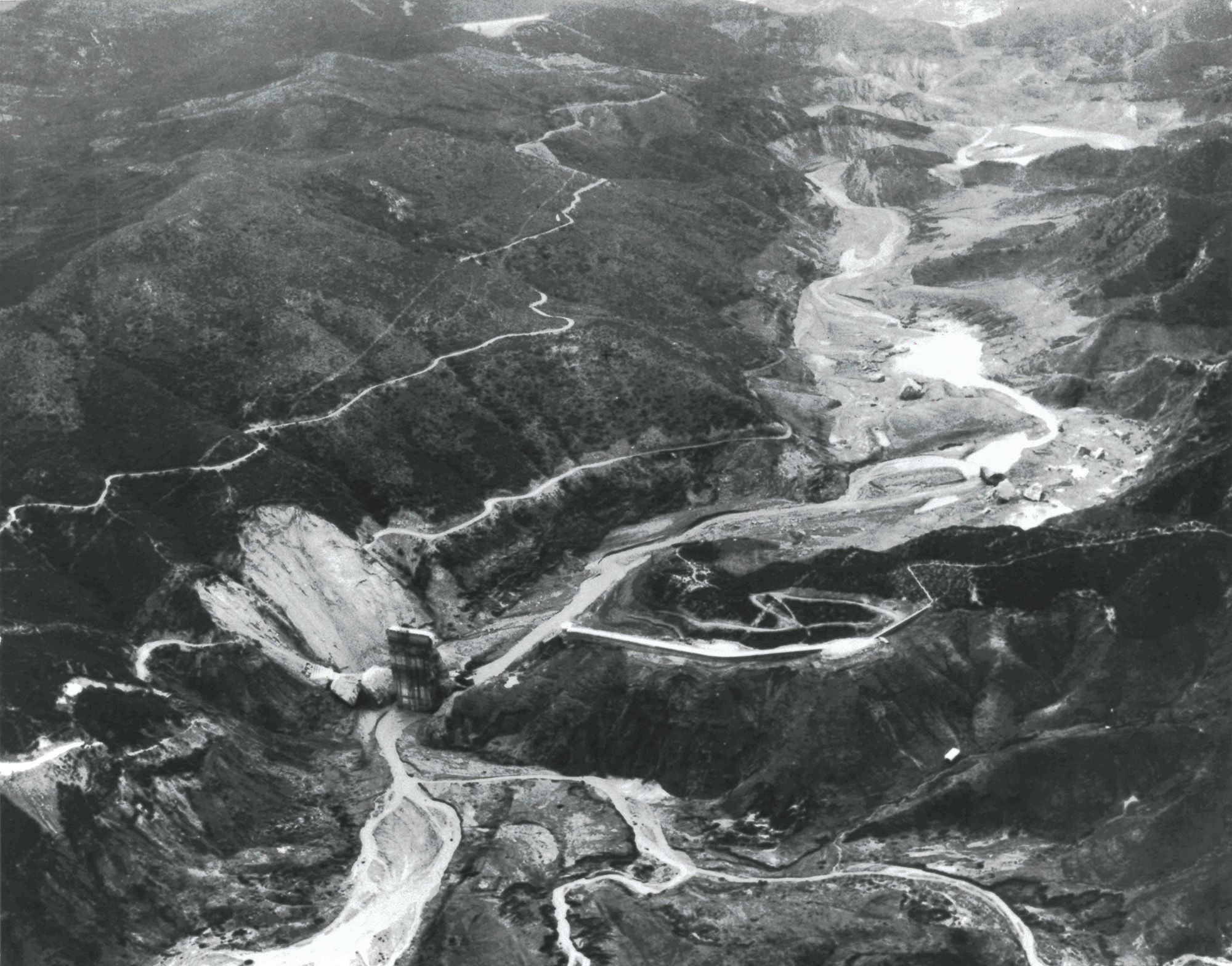 An aerial view of San Francisquito Canyon after the St. Francis Dam collapsed in 1928. The dam’s surviving center section is visible near the bottom, where the steep canyon walls channeled the flood downstream.